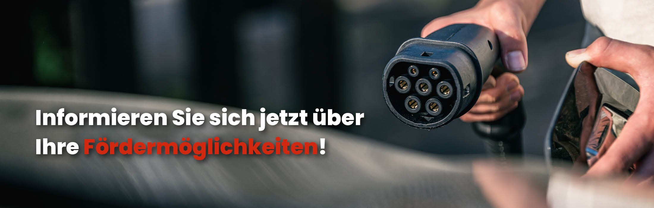 Hand hält Ladekabel das an Elektroauto angeschlossen wird